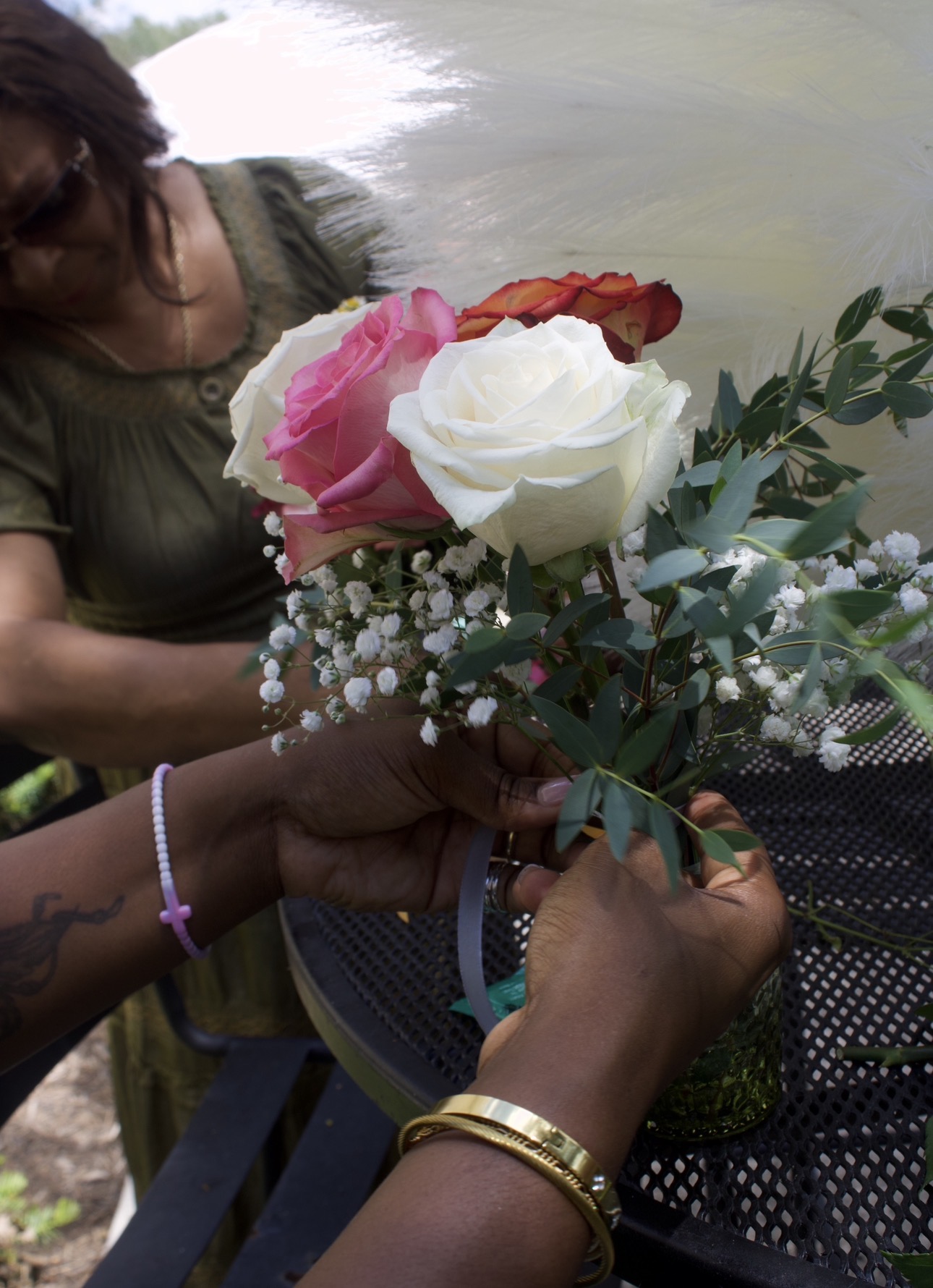 Close-up of hands tying ribbon around a rose and baby's breath arrangement at the bridal shower