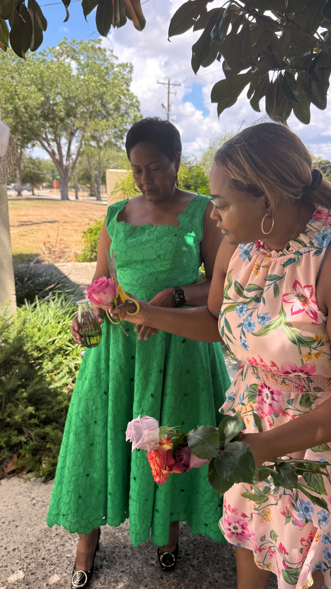 Two guests trimming pink and coral roses into bud vases outdoors