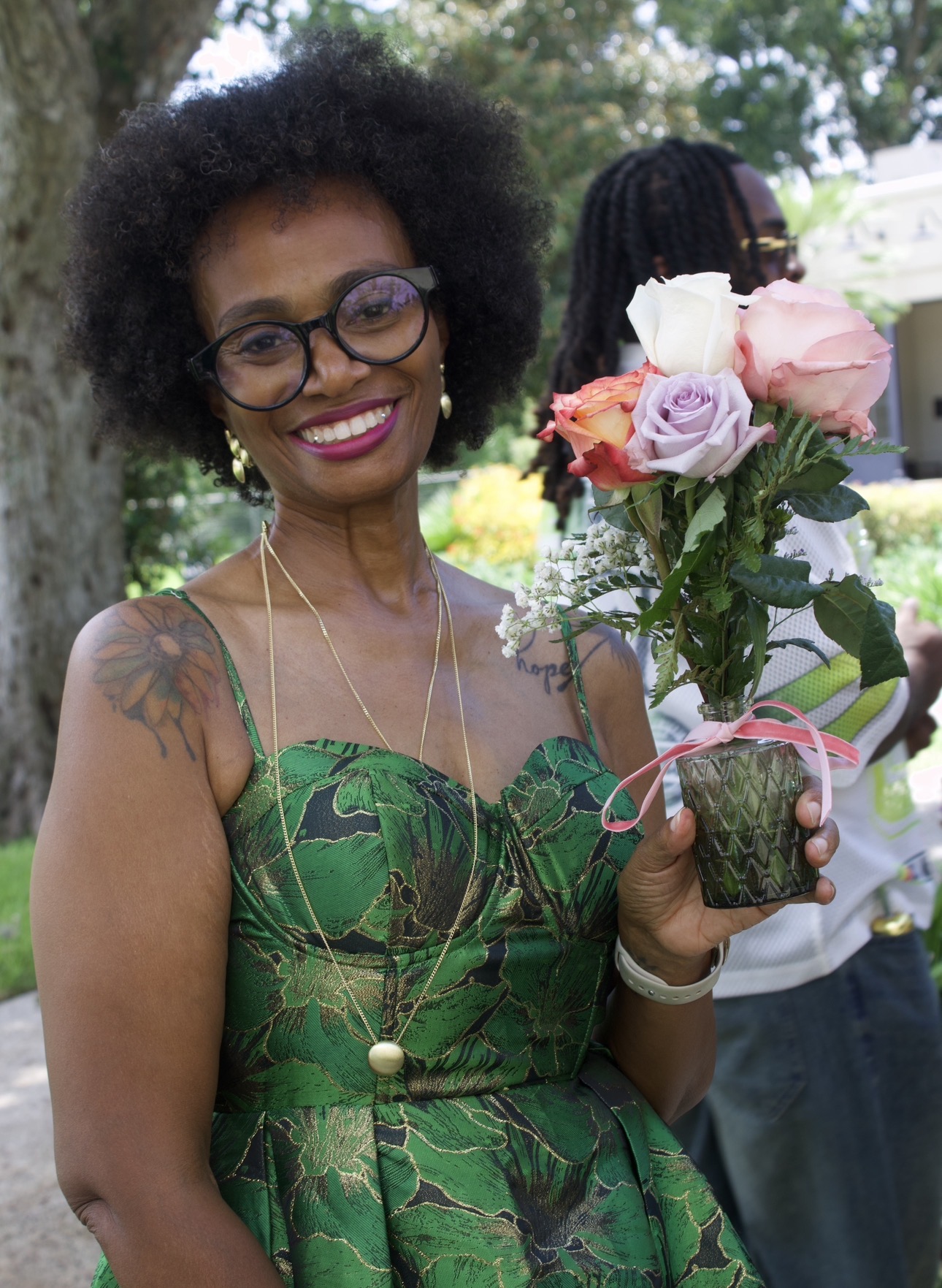 Mother of the bride smiling with the rose bud vase arrangement she designed at the bridal shower