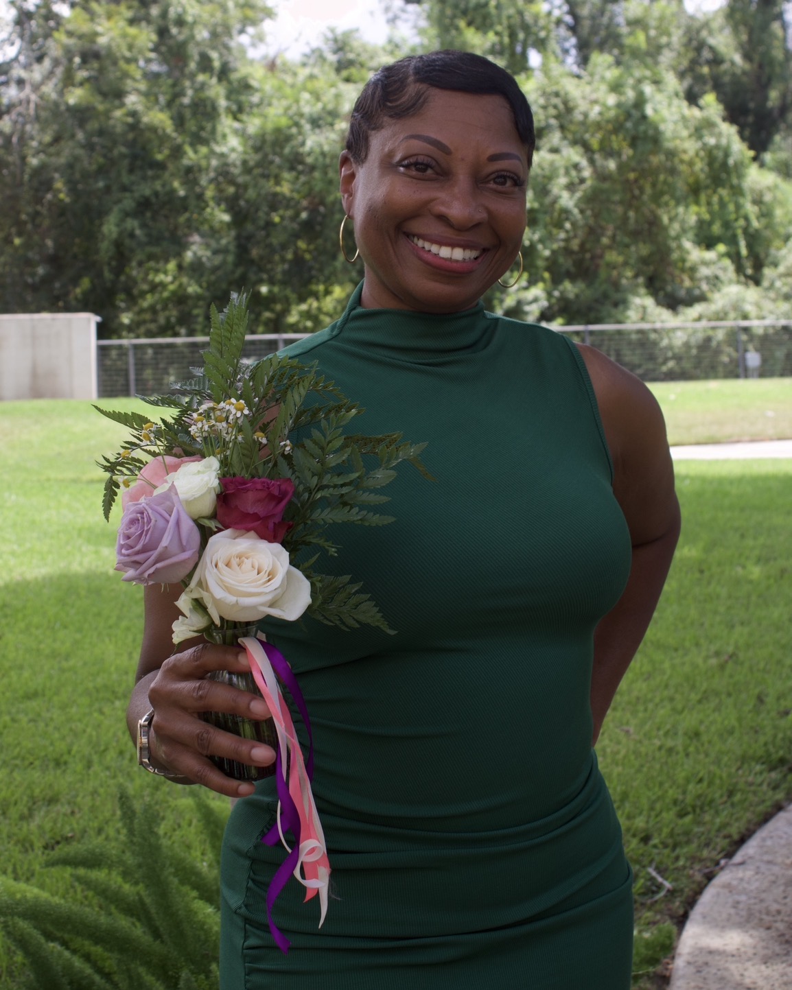 Guest holding her finished rose and fern bouquet with ribbon streamers at the bridal shower
